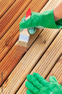 A worker applying varnish to a near-finished fence