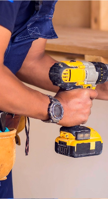 A handyman using a drill to screw nails into a wall
